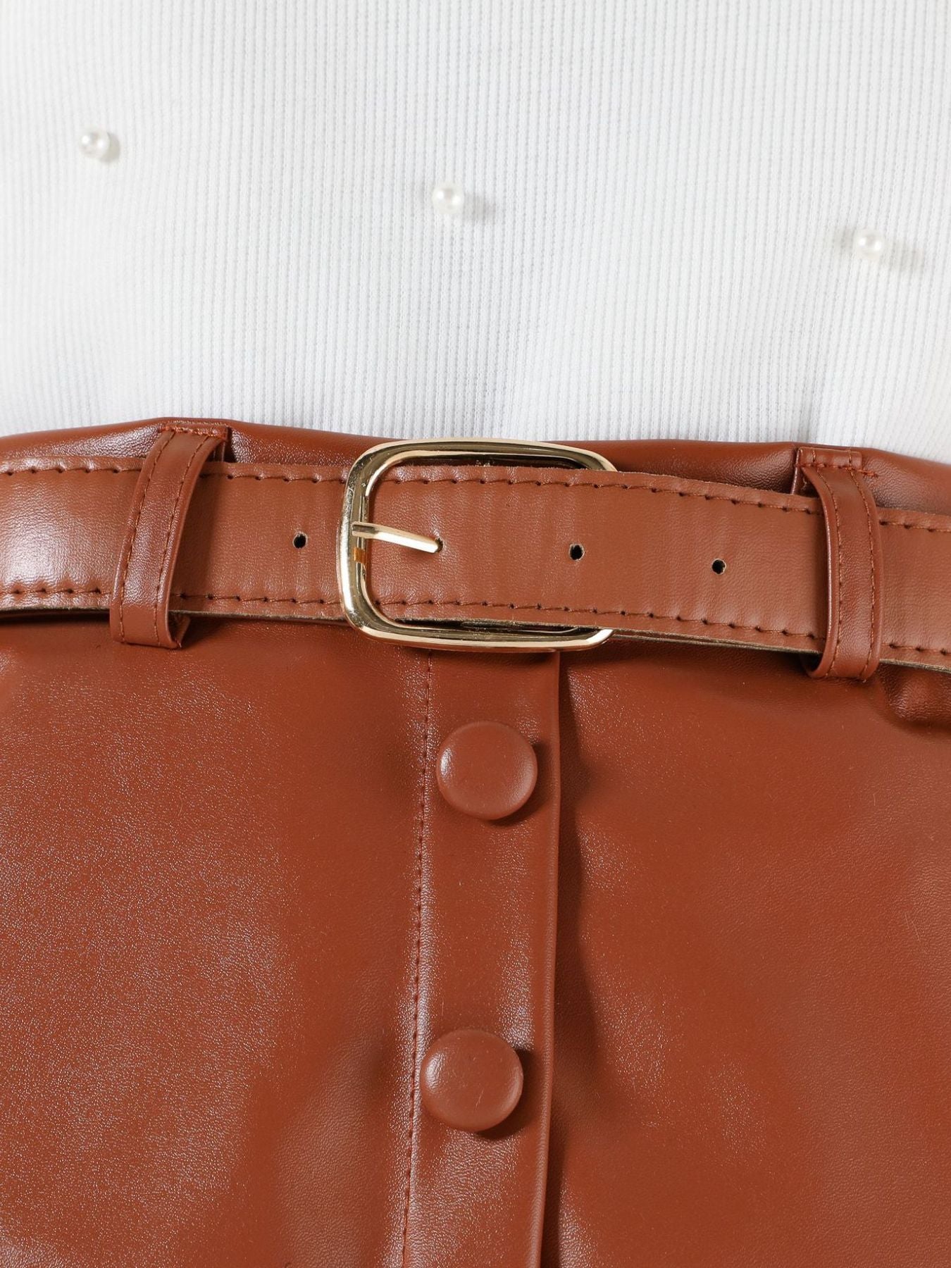 Toddler white pearl-embellished top with brown faux leather skirt, belt, and button detail.