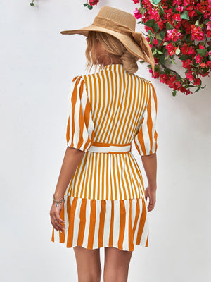 Vertical stripe shirred waist dress in gold with puff sleeves and tiered skirt.