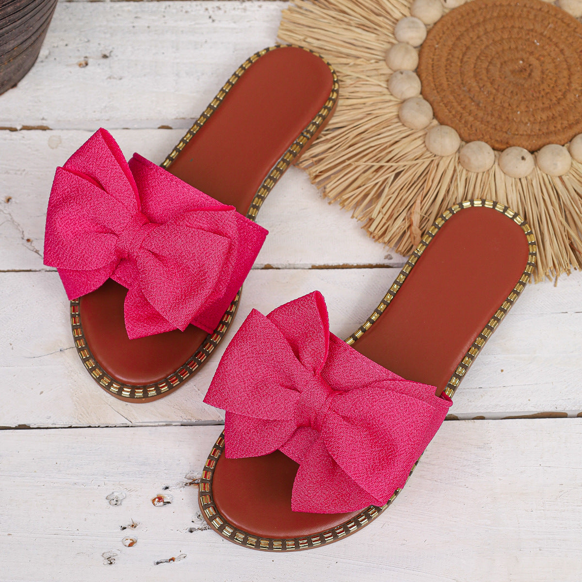 Fuchsia pink bowknot sandals with brown soles and beaded trim.