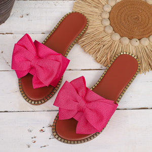 Fuchsia pink bowknot sandals with brown soles and beaded trim.