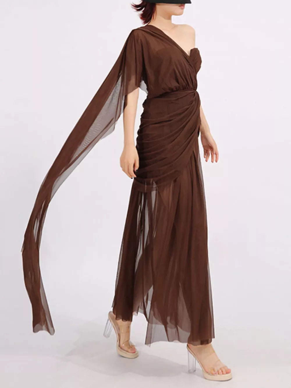 Draped one-shoulder maxi dress in coffee brown with sheer fabric and flowing sleeve detail.