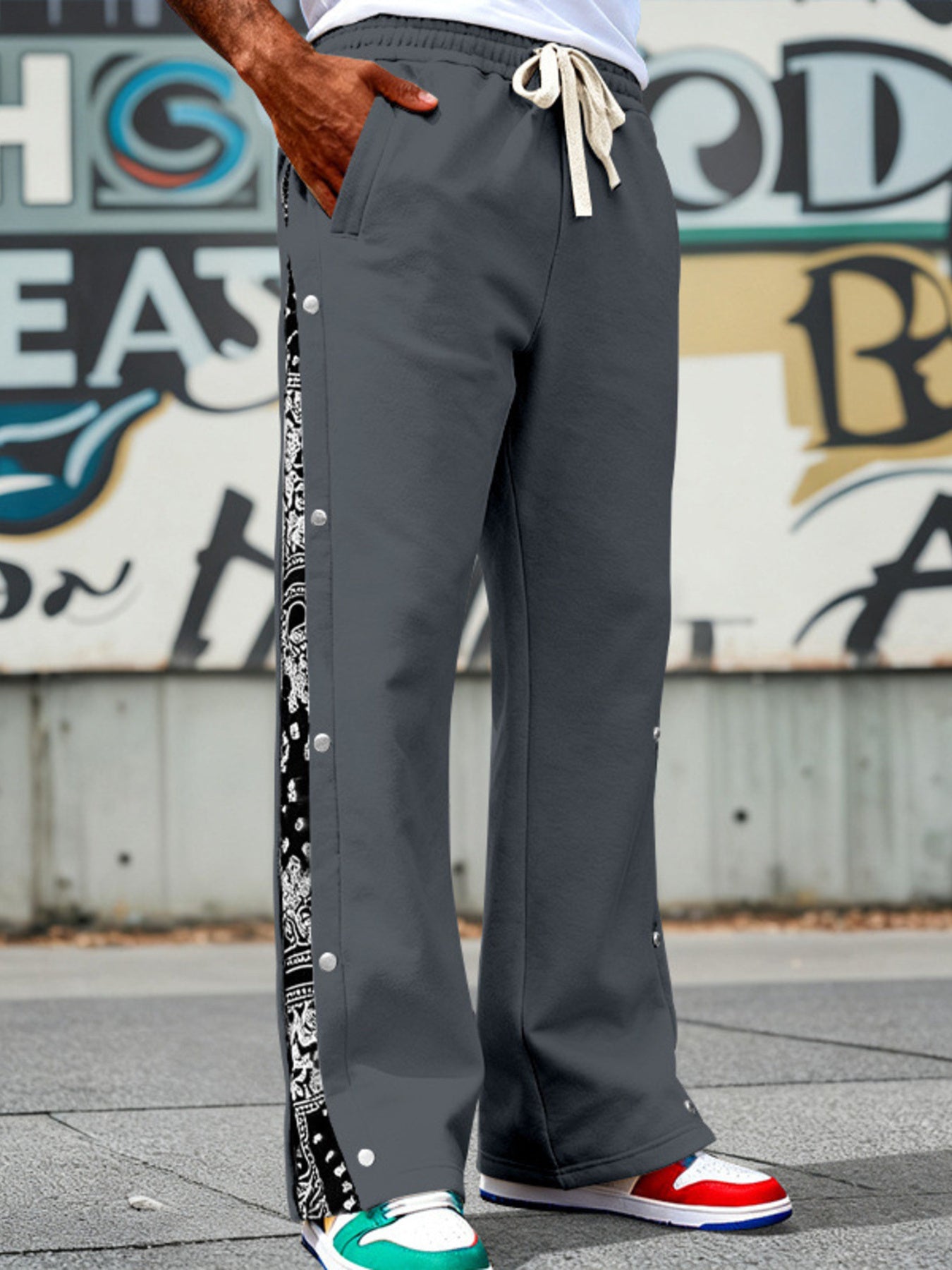 Men's dark gray sweatpants with drawstring and side snaps, featuring a paisley stripe detail.