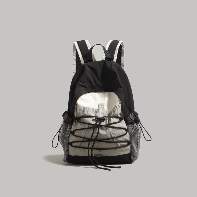 Black and grey nylon drawstring backpack with bungee cord detail and mesh pockets.