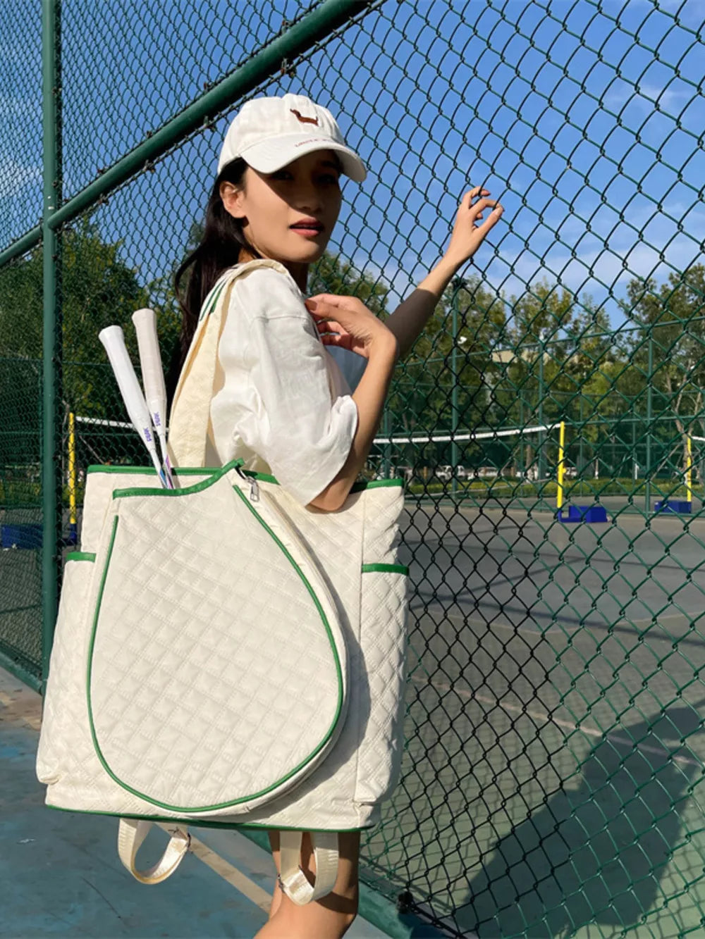 Off-white quilted sports racket backpack with green trim, tennis rackets visible.