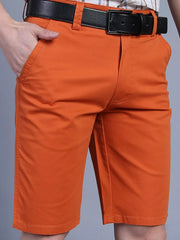Men's orange chino shorts with belt and pockets, casual style.