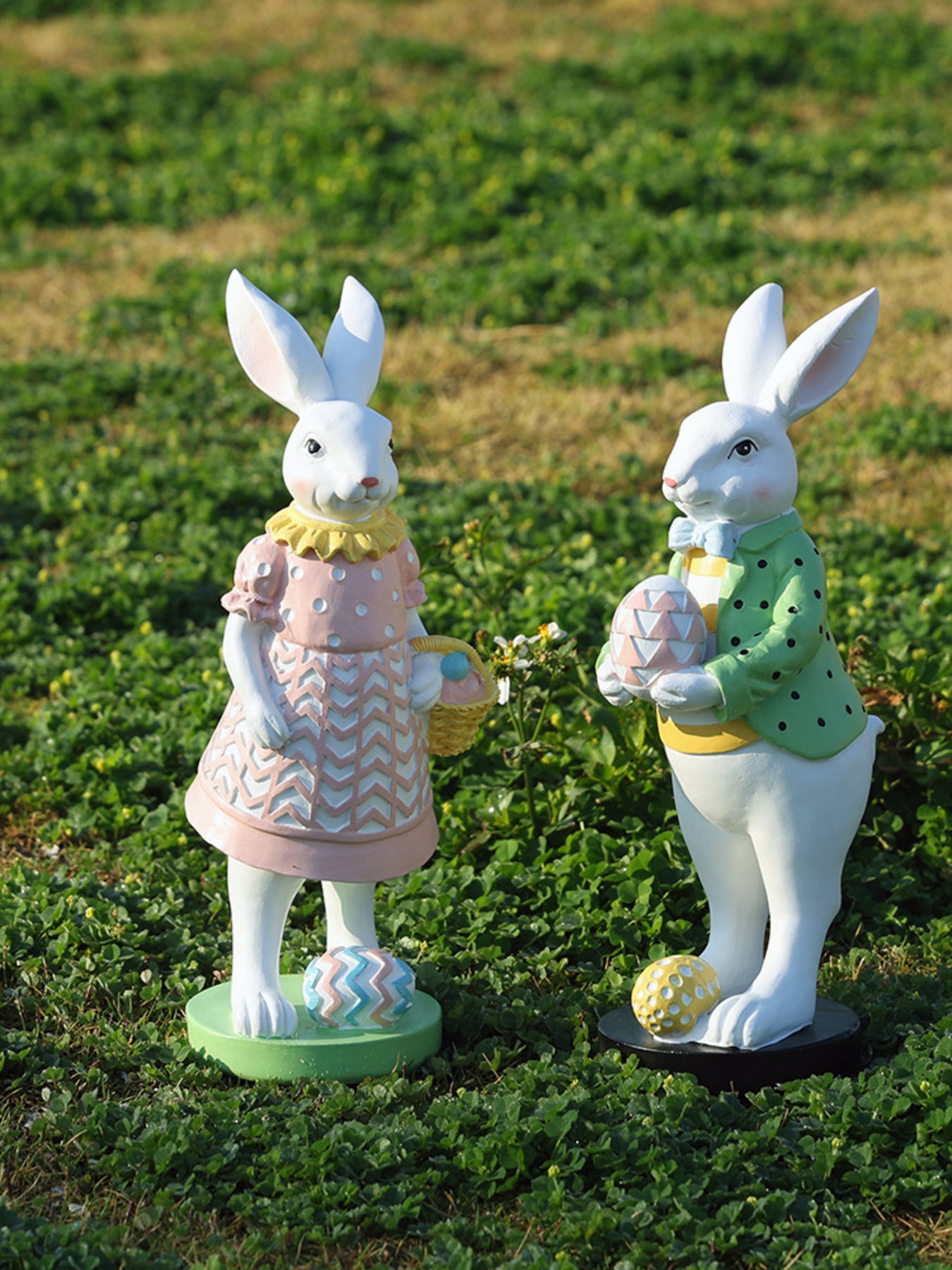 Easter bunny figurines in blush pink and gum leaf green holding eggs and baskets.