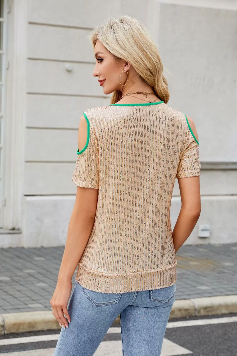Tan sequin cold shoulder blouse with green trim and short sleeves.