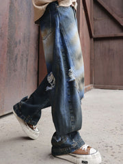 Men's dark distressed wide-leg denim jeans with rips and faded details.