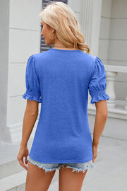 Blue tee with puffed sleeves, ruffled cuffs, and a tie-neck detail.