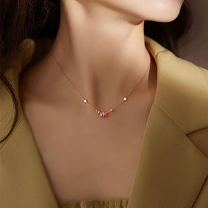Rose gold necklace with a fine chain, featuring a central cluster of colorful rings and small clear stones.