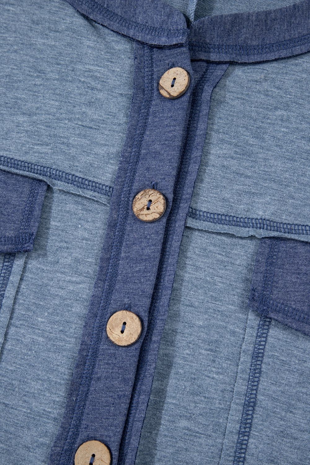 Denim-trimmed dusty blue utility jumpsuit with wooden buttons and contrast stitching.