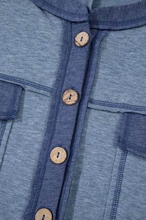 Denim-trimmed dusty blue utility jumpsuit with wooden buttons and contrast stitching.