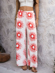Geometric print wide-leg drawstring trousers in white with red sun pattern.