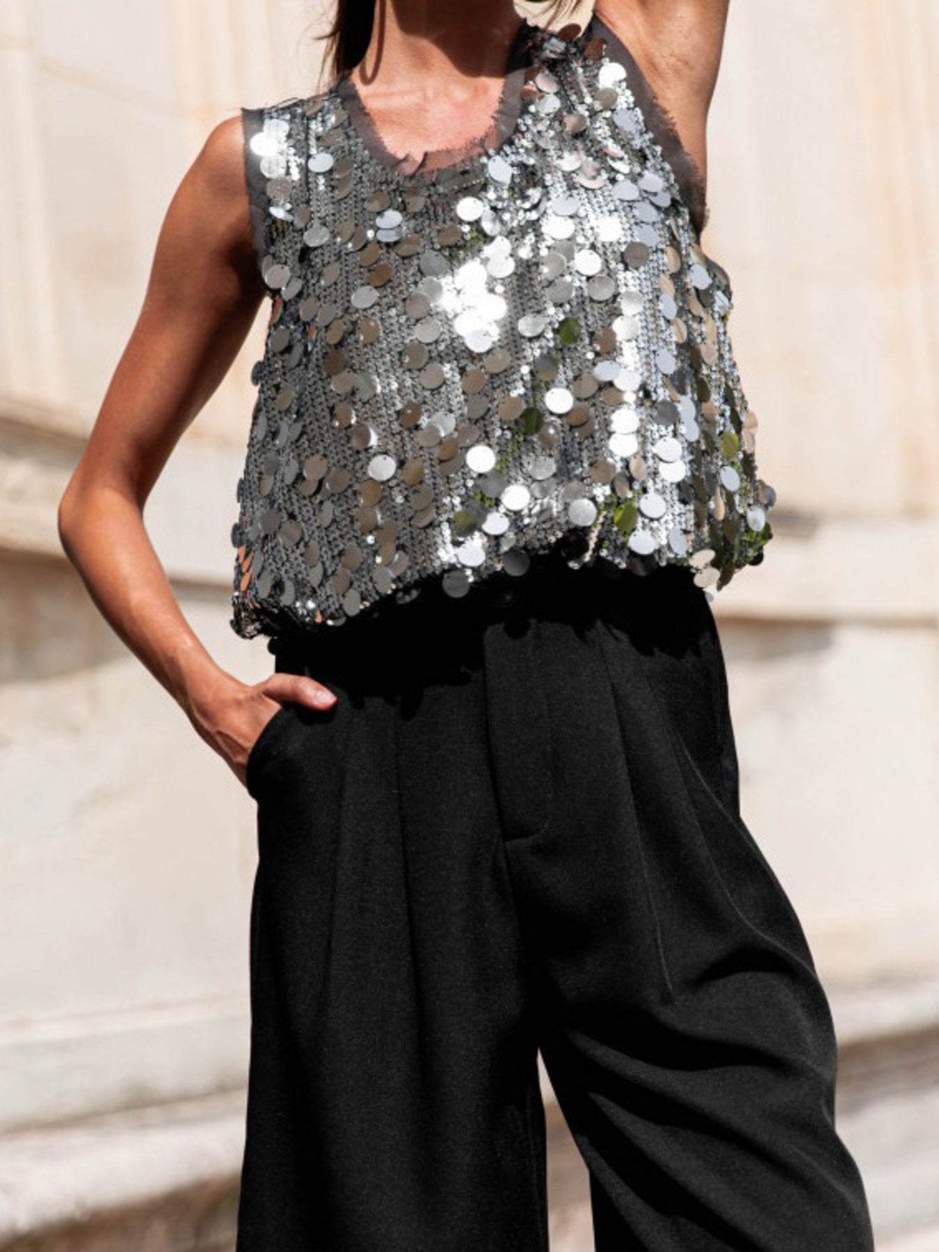 Gray sequin tank top with frayed neckline, worn with black pants.