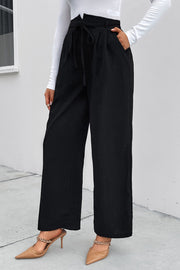 Black high-waist palazzo trousers with tie detail and pockets, styled with heels.