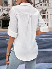 White textured collared shirt with rolled sleeves and a curved hem, styled casually.