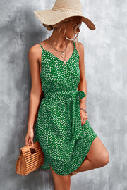 Green daisy print slip dress with tie waist and V-neck, styled with a straw hat.