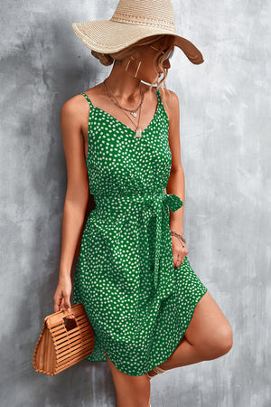 Green daisy print slip dress with tie waist and V-neck, styled with a straw hat.