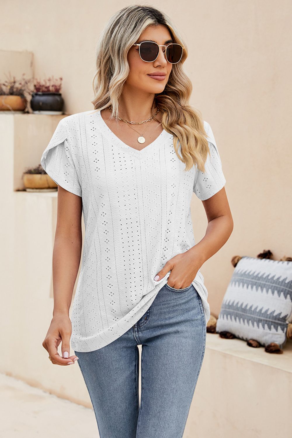 White eyelet knit top with short sleeves and V-neck, featuring perforated sleeve detail.