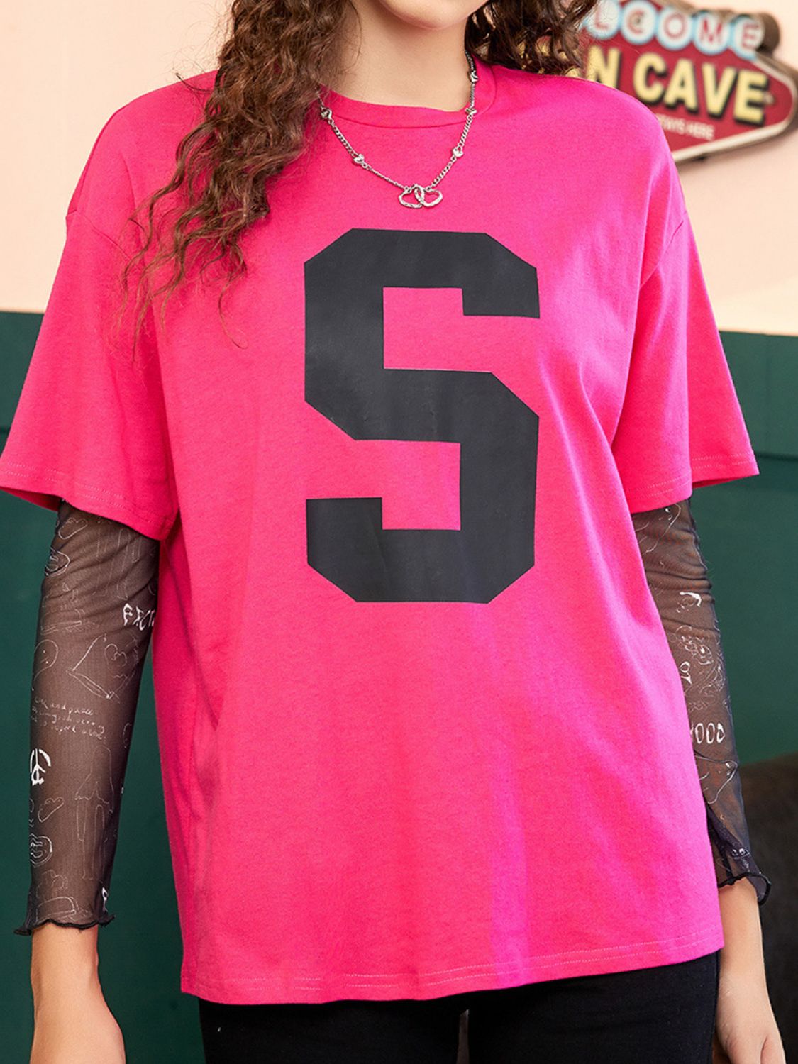 Varsity number tee in bright pink with black mesh sleeves featuring graphic print.