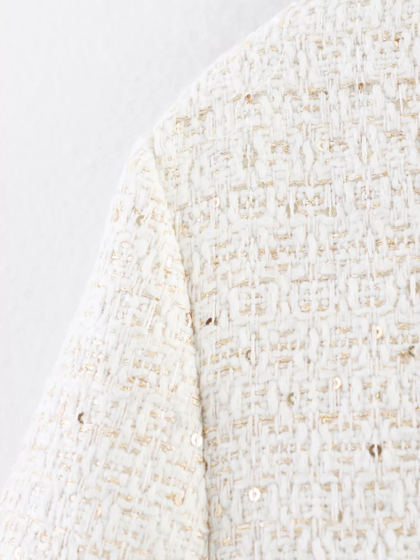 White tweed cropped jacket with gold sequins and button-up detail.