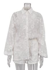 White embroidered two-piece shirt and shorts set with button-down shirt and elastic waist shorts.