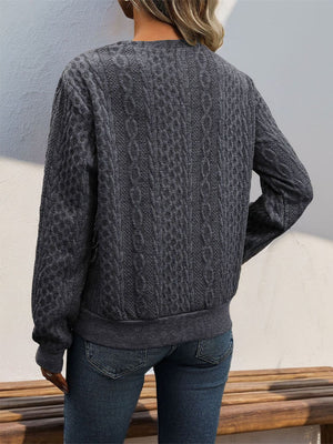 Dark gray cable knit sweater with asymmetric button-neck detail and ribbed cuffs and hem.