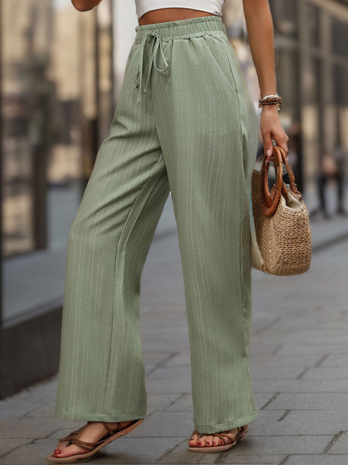 Sage linen blend palazzo trousers with drawstring and subtle vertical pinstripes.