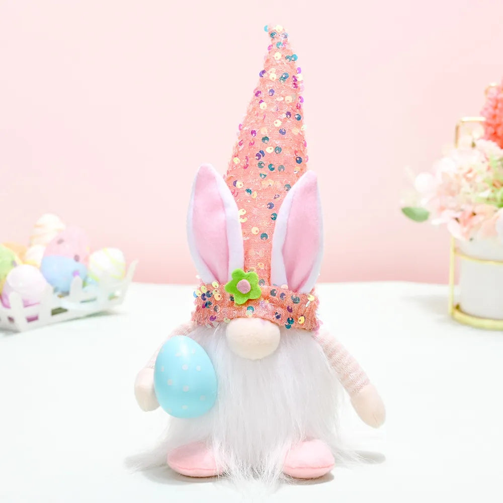 Easter bunny gnome with sequin cone hat and pink bunny ears holding a blue egg.