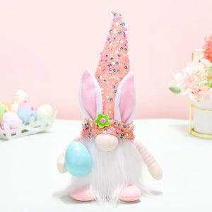 Easter bunny gnome with sequin cone hat and pink bunny ears holding a blue egg.