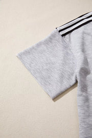 Grey relaxed t-shirt with black and white shoulder stripes and raw hem sleeves.