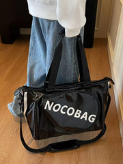 Black gym duffel bag with white text and stripes, featuring a detachable strap.