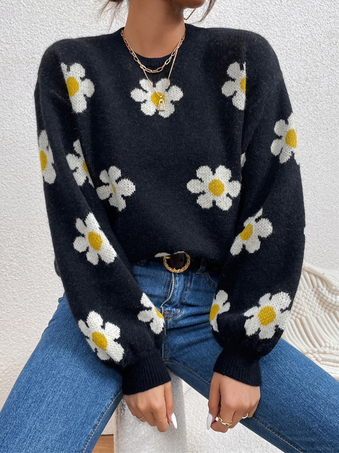 Black knit sweater with white and yellow daisy print and puff sleeves.