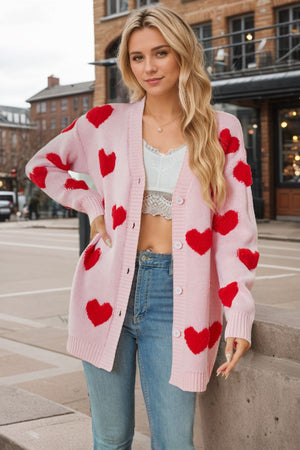 Pink acrylic knit cardigan with red heart appliques, button front, and ribbed cuffs.