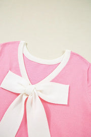 Pink knit top with white contrast trim and a large white bow detail on the front.
