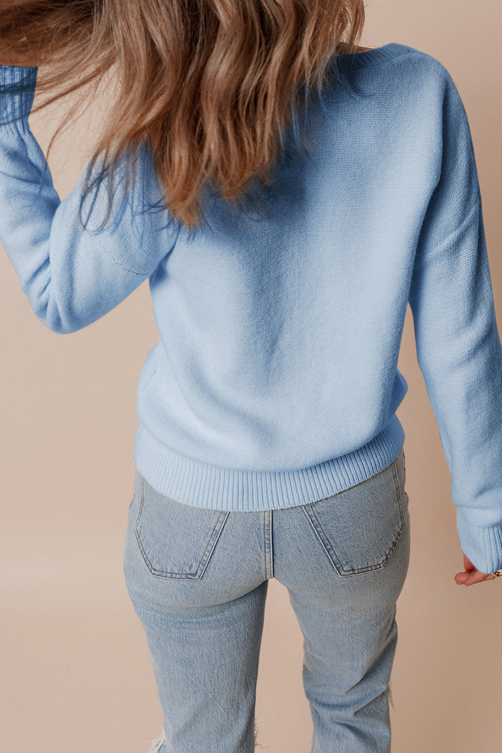 Light blue knit sweater with ribbed cuffs and hem, styled with jeans.