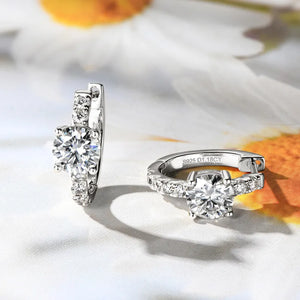 Silver pavé-set moissanite huggie hoop earrings with a central round-cut stone.