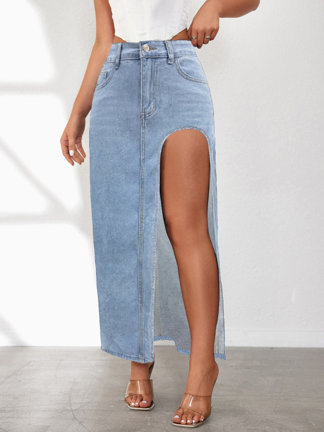 Light blue denim maxi skirt with a high slit and button-fly closure.