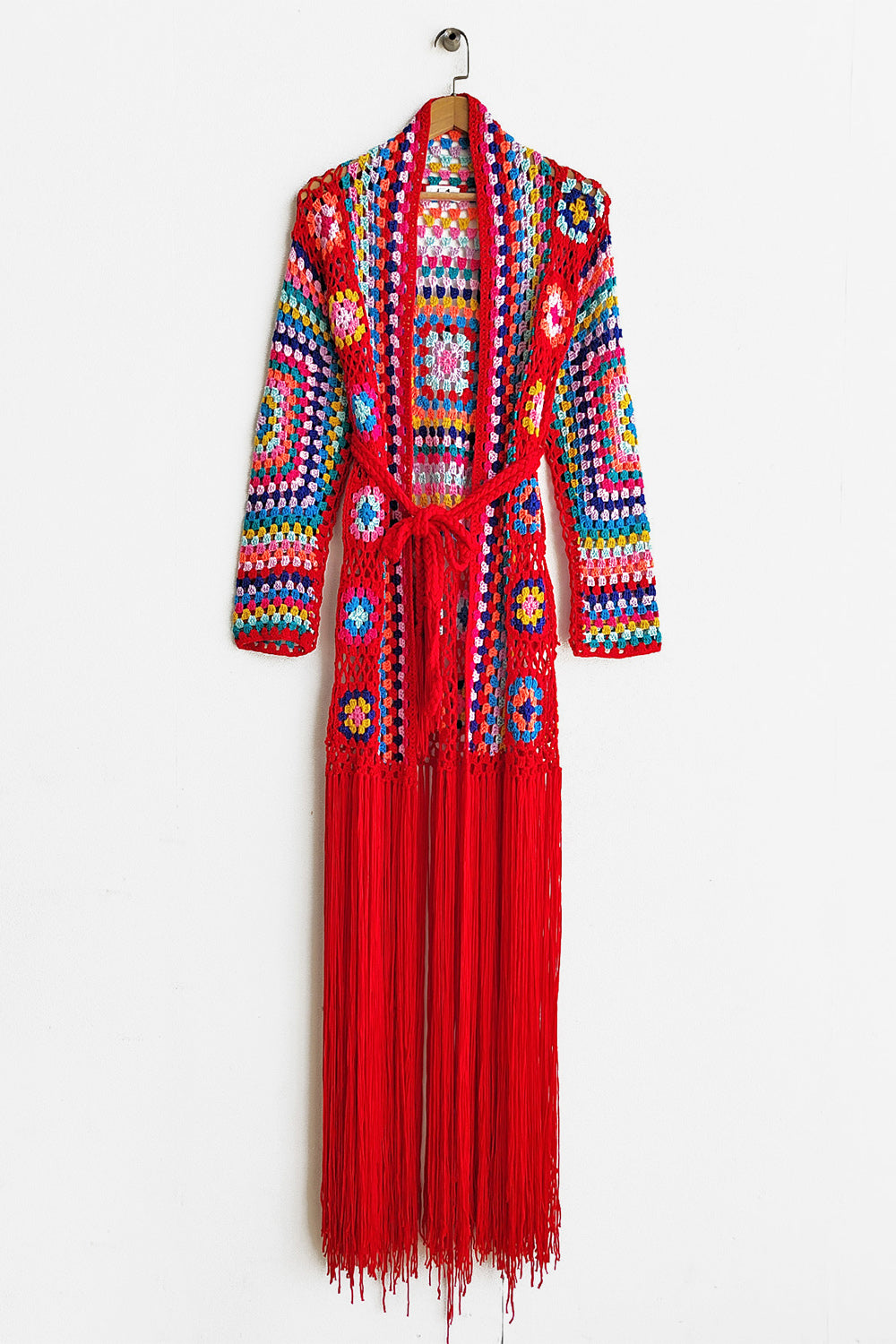 Granny square crochet duster in red with colorful squares and long fringe detail.