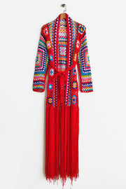 Granny square crochet duster in red with colorful squares and long fringe detail.