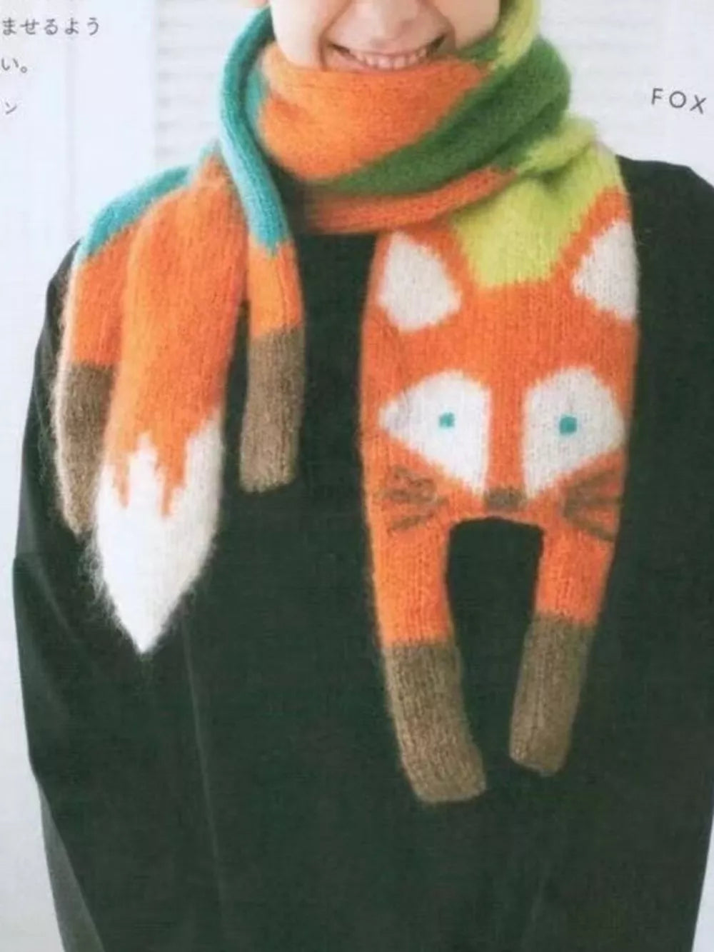 Chunky knit scarf with a fox face design in orange, white, and brown, with colorful stripes.