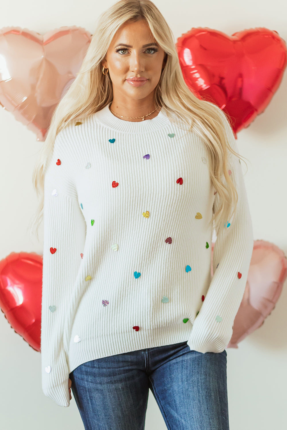 White ribbed knit sweater with multicolor heart embellishments.