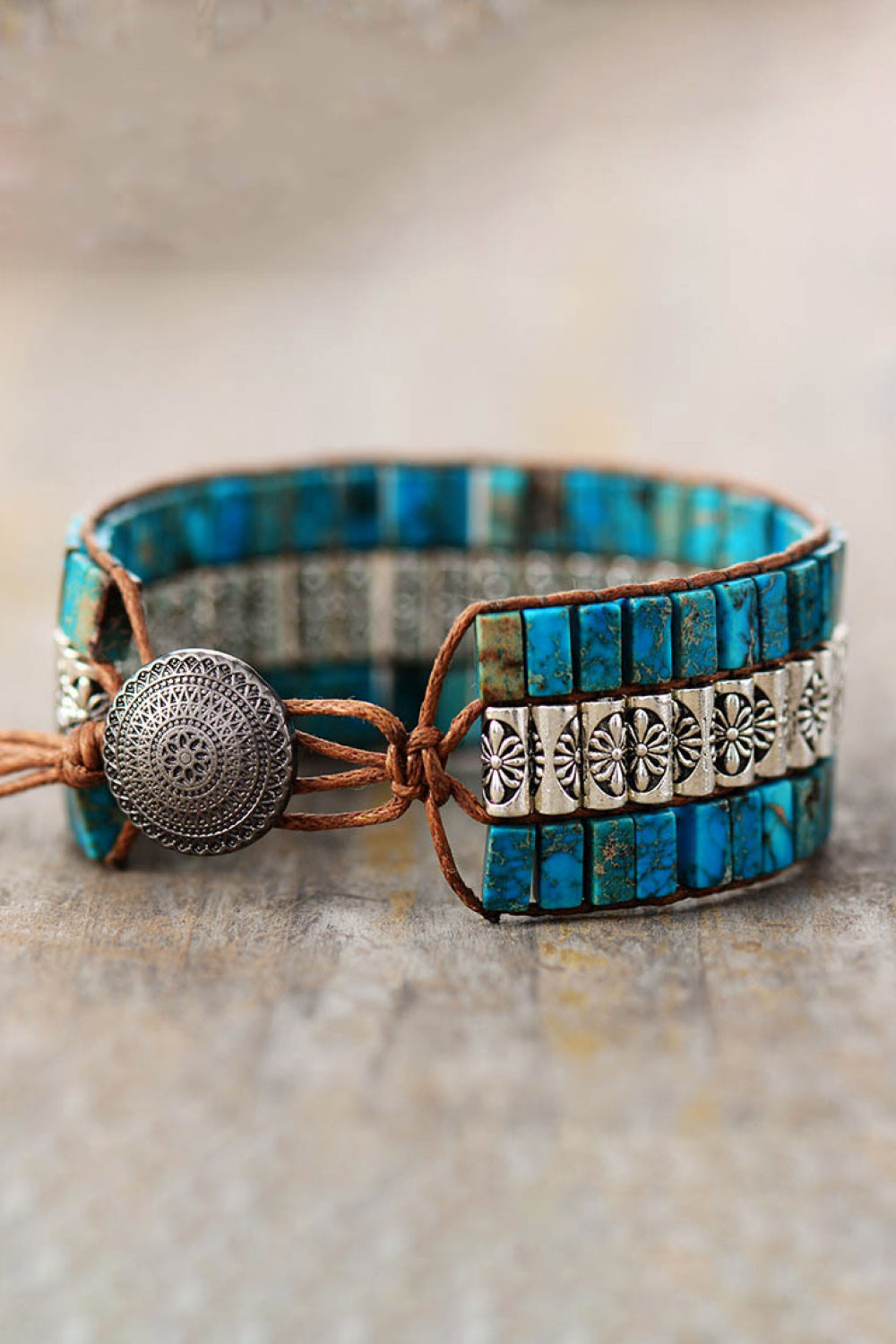 Turquoise tile and floral accent bracelet with leather cord and metal button closure.