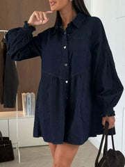 Dark blue denim mini dress with pockets, button-down front, and smocked cuffs.