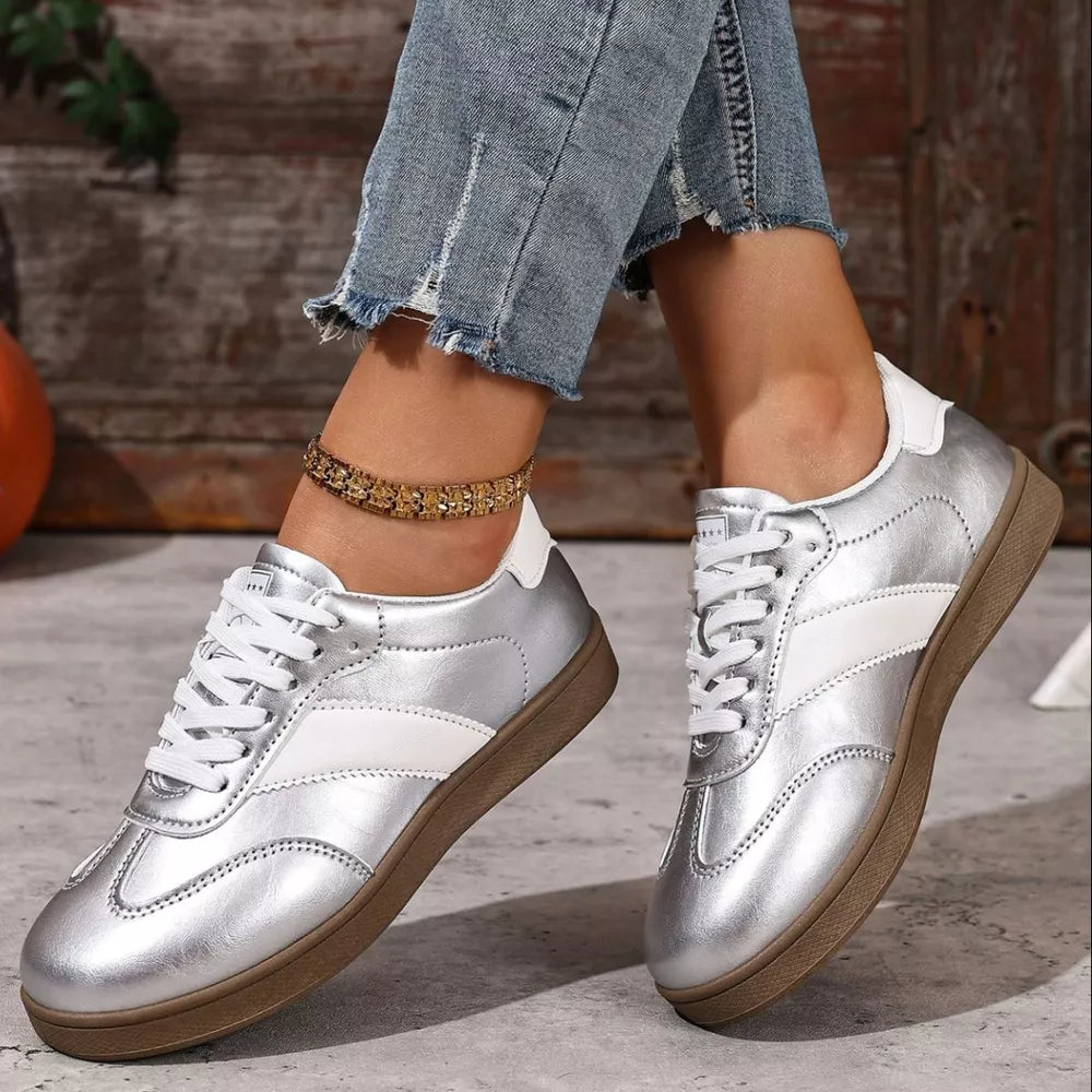 Silver patent leather lace-up sneakers with white accents and brown soles.