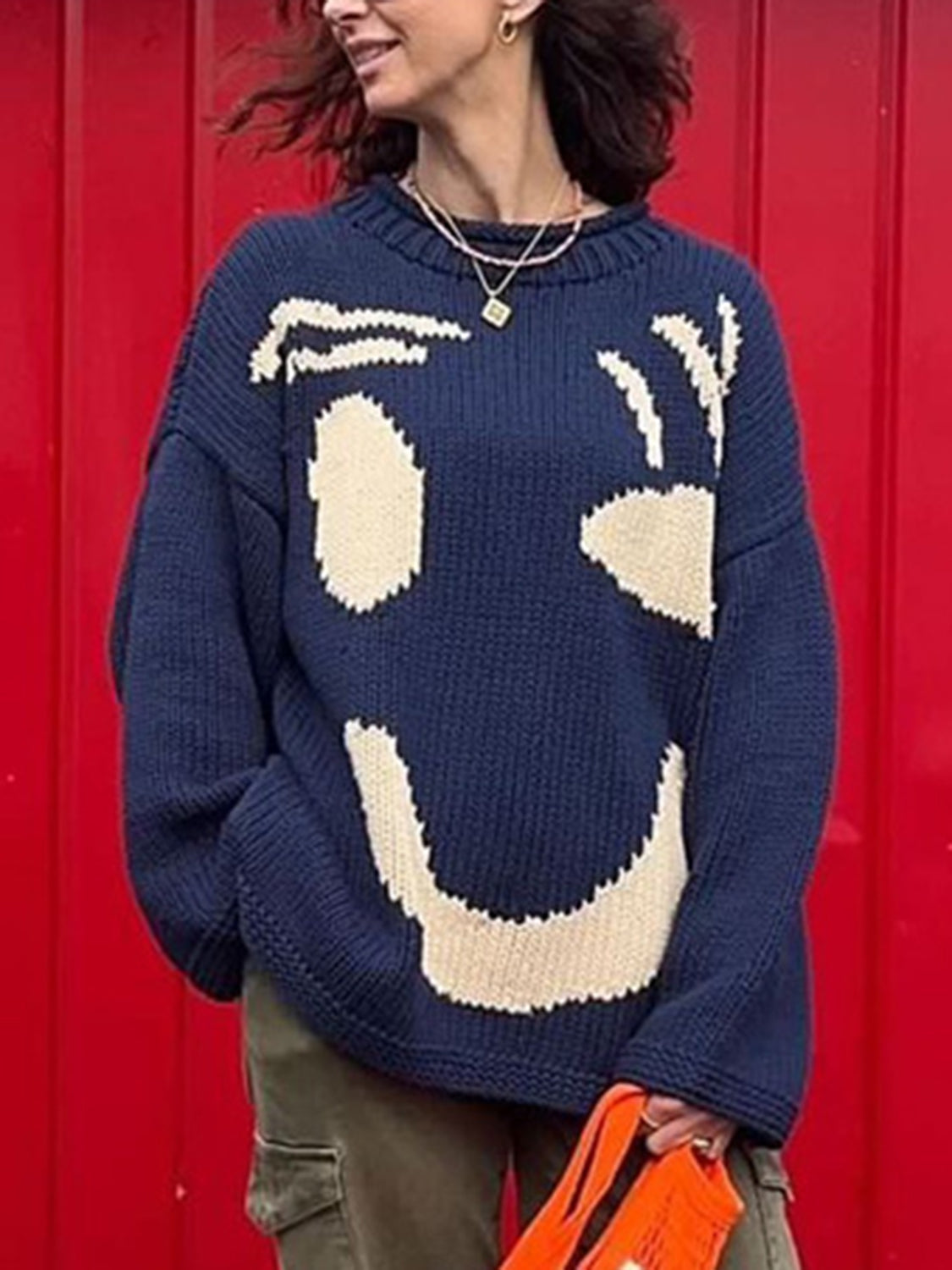 Dark blue knit sweater with abstract cream graphic face pattern, crew neck, long sleeves.