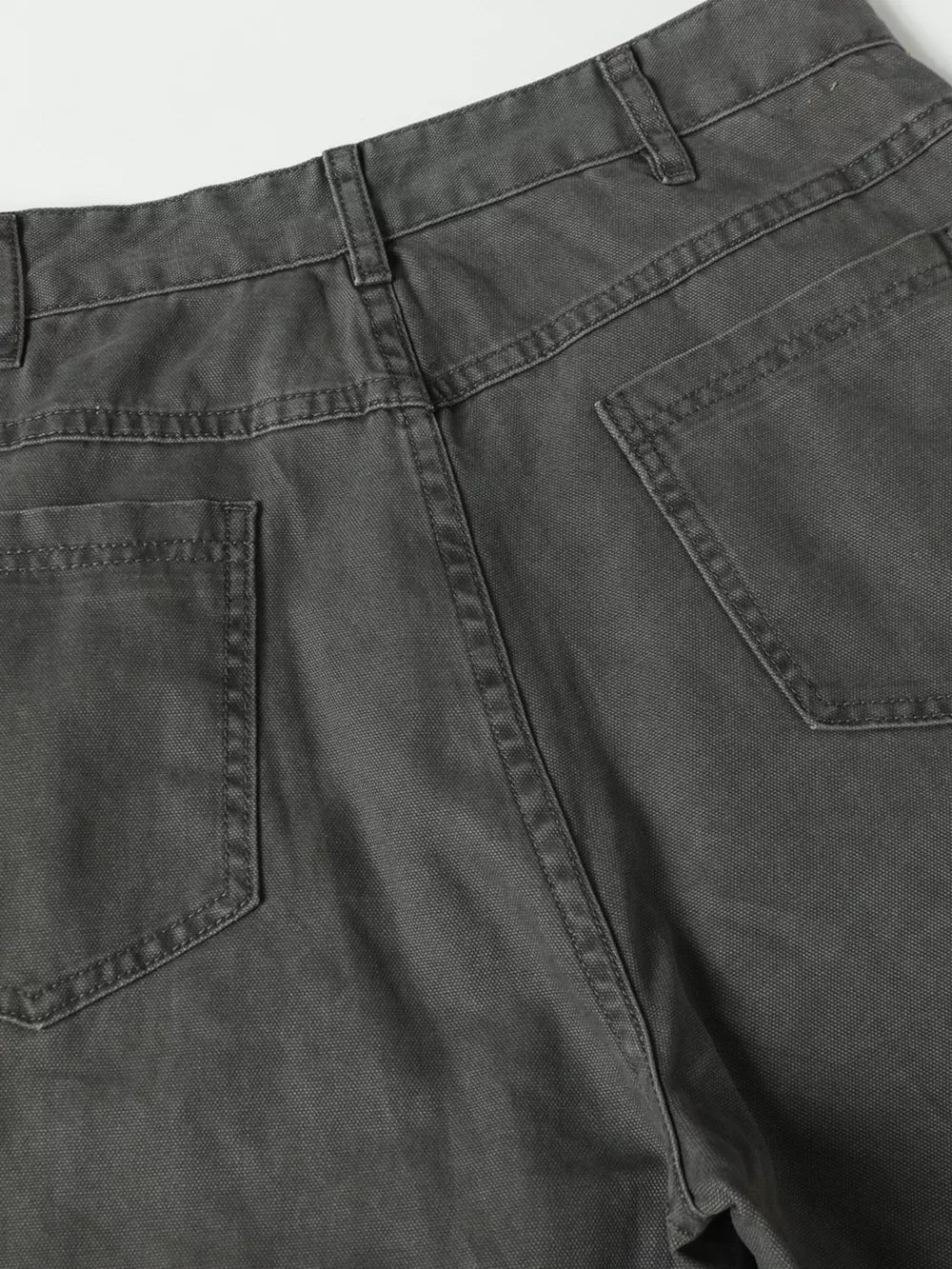 Grey cargo pants with buckle detail and pockets, showing back view and stitching.