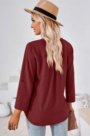 Burgundy textured henley shirt with roll-tab sleeves and a curved hem.