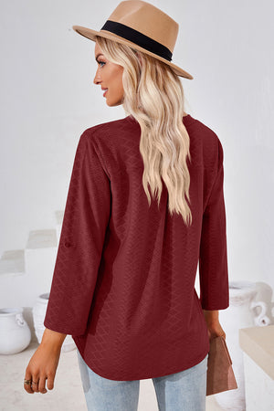 Burgundy textured henley shirt with roll-tab sleeves and a curved hem.
