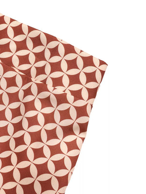 Chic one-shoulder top and geometric maxi skirt set in cream with a brown pattern.